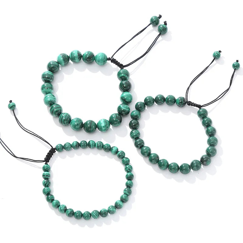 Trois bracelets en perles de malachite verte avec des motifs concentriques noirs, sur fond blanc.