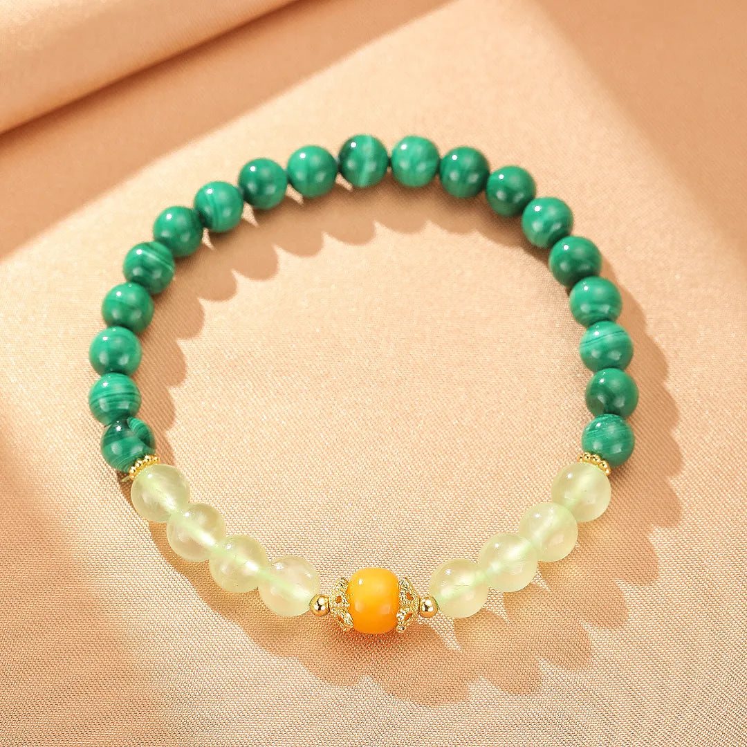 Bracelet "Harmonie Colorée" fait de perles de Malachite verte, de Préhnite pâle et d'une perle centrale Ambre orangée, avec des intercalaires dorés.