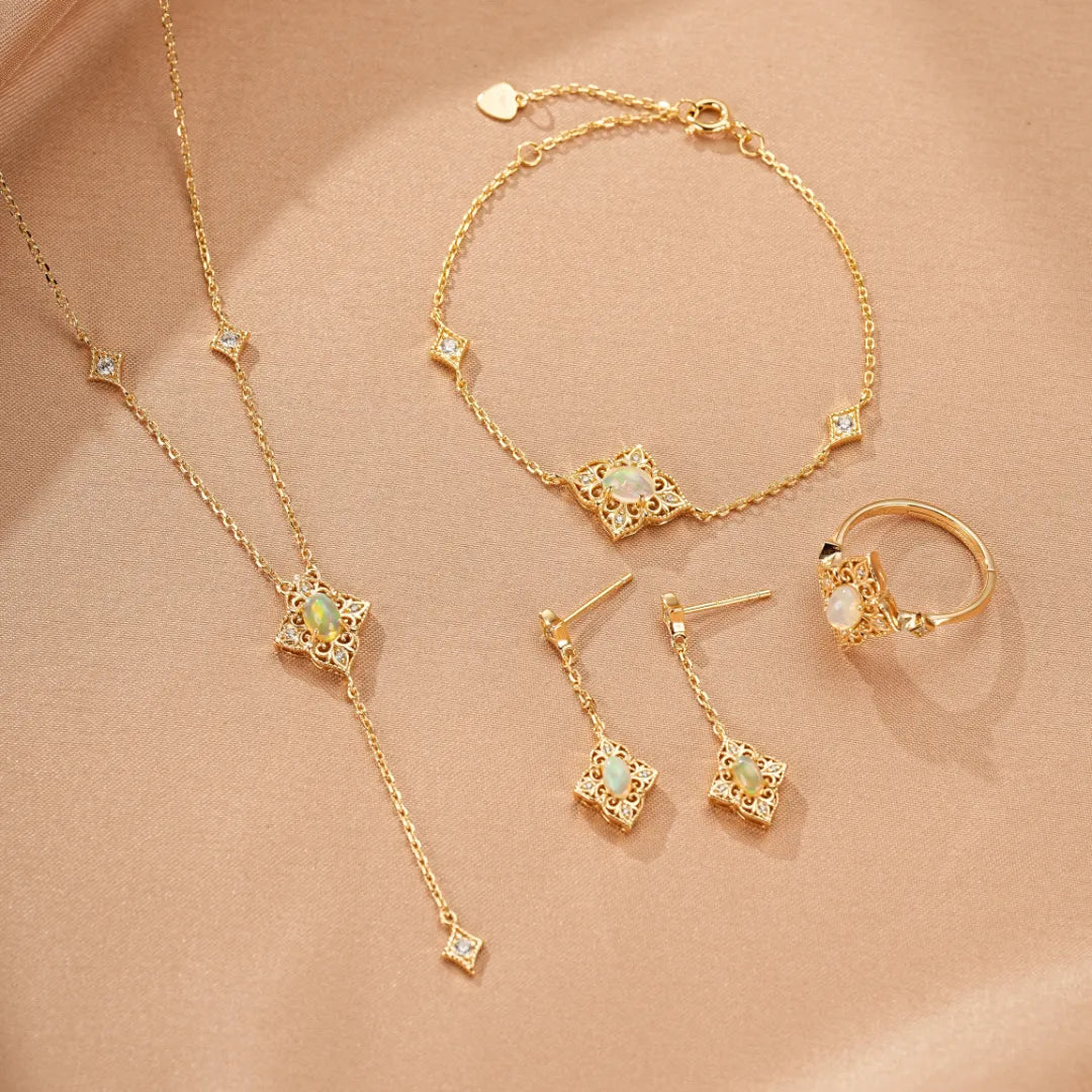 Ensemble de bijoux en argent doré avec opales et zircons cubiques : collier, bracelet, bague et boucles d'oreilles en forme de fleur stylisée.