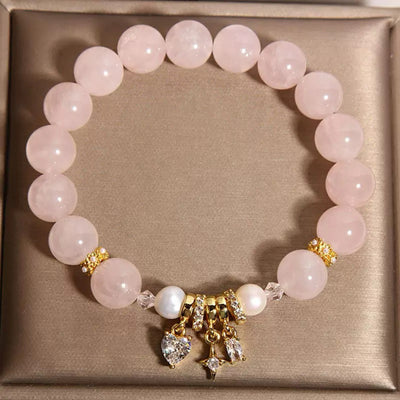 Bracelet en quartz rose et perles "Douceur Céleste" avec breloques en forme de cœur et d'étoile serties de cristaux et d'éléments dorés.