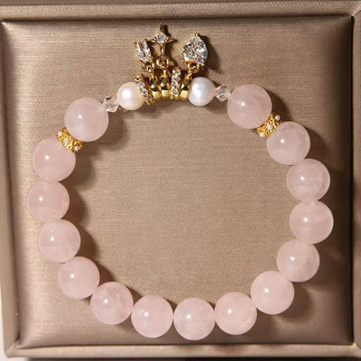 Bracelet en quartz rose et perles avec un pendentif couronne orné de zircons et d'une perle centrale.