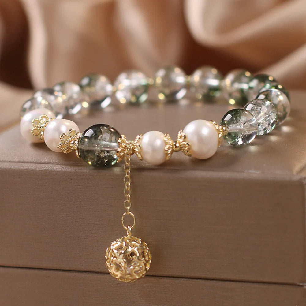 Bracelet élégant en quartz vert et perles d'eau douce, rehaussé d'une breloque sphérique dorée ajourée et de détails floraux dorés.