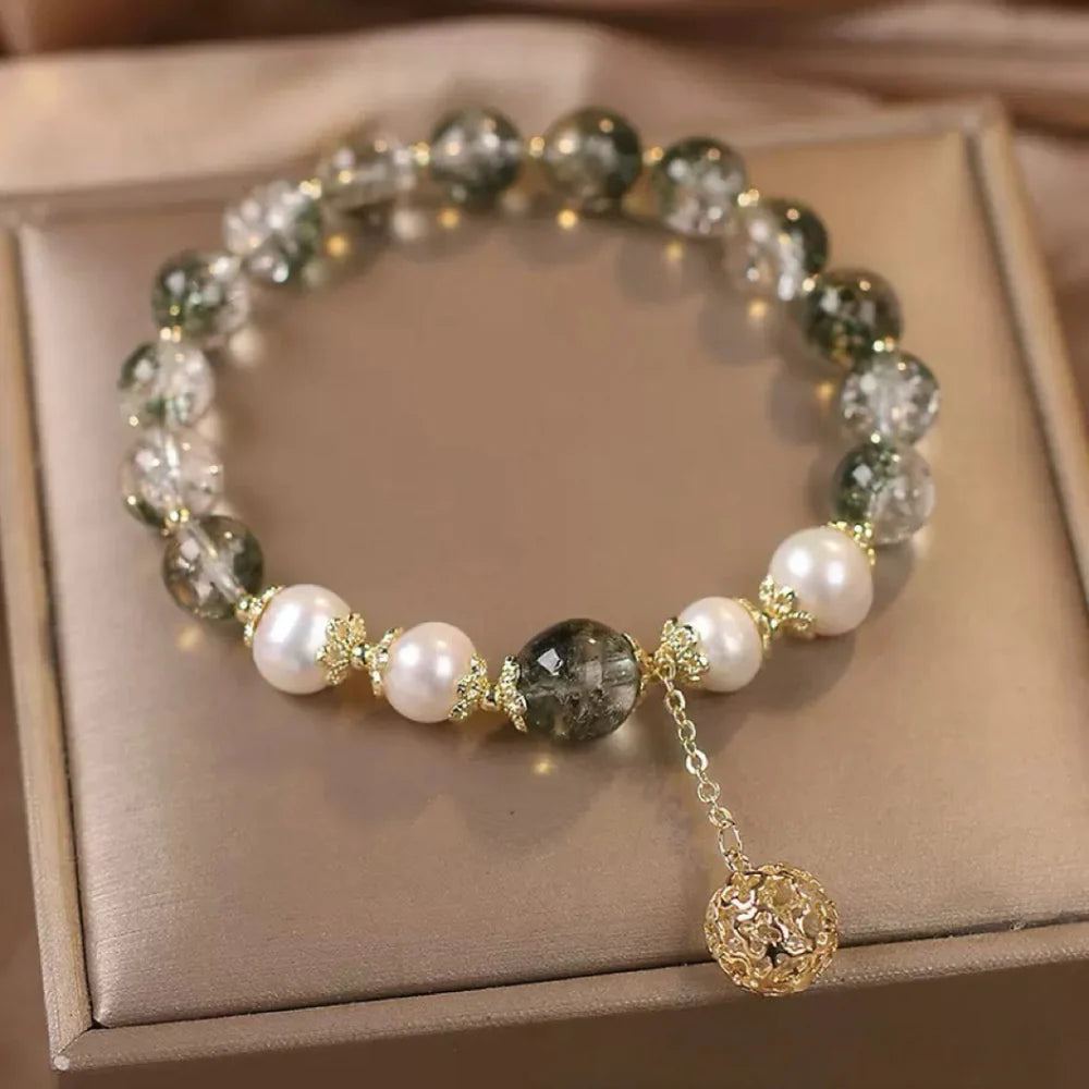 Bracelet en quartz vert et perles nacrées avec une breloque sphérique dorée ajourée.