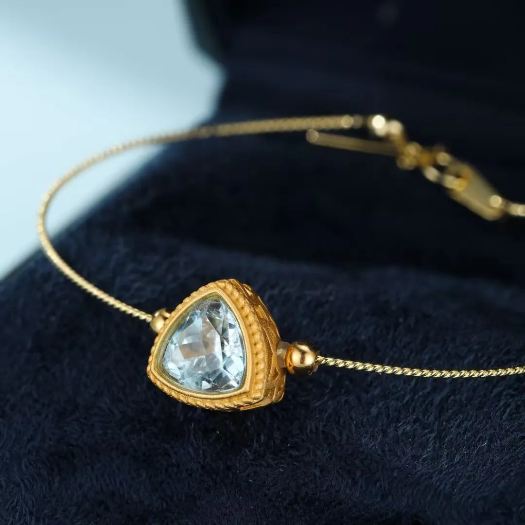 Bracelet en argent doré or avec une topaze bleue en forme de triangle "Harmonie Céleste" sertie dans un entourage texturé.