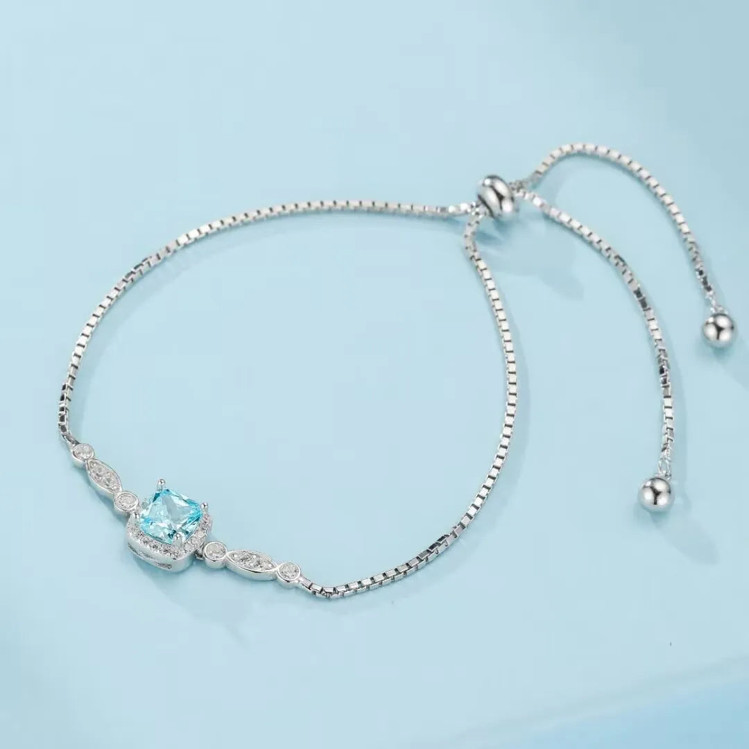 Bracelet jonc en argent 925 avec une topaze bleu ciel carrée sertie entourée de petits cristaux scintillants.