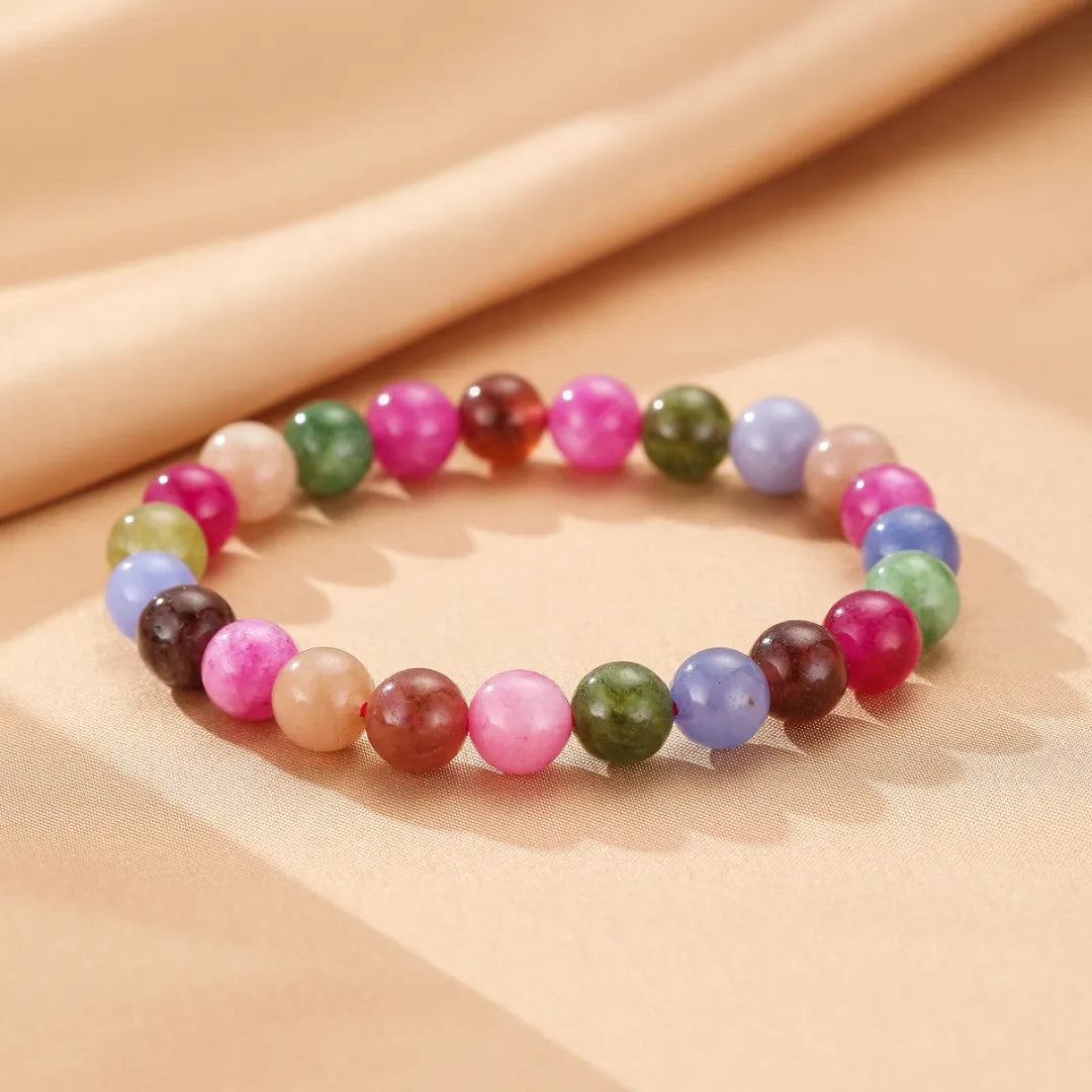 Bracelet "Équilibre Coloré" fait de perles de tourmaline multicolores sur fond beige clair.