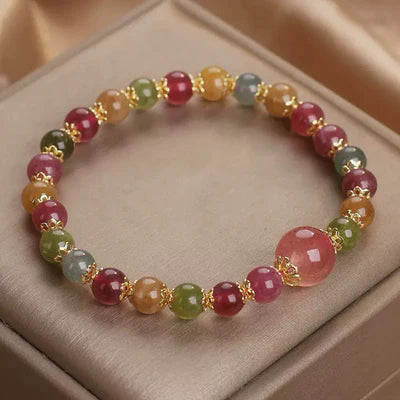 Bracelet "Lumière Colorée" fait de perles rondes de tourmaline et de quartz fraise dans des tons roses, verts, jaunes et bleus, séparées par des éléments dorés. Une grosse perle rose translucide est mise en évidence.