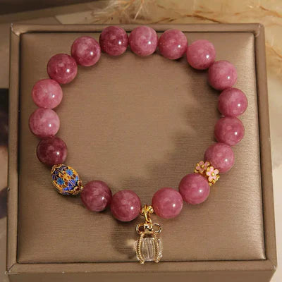 Bracelet "Raffinement Impérial" en tourmaline rose et cristal de roche, orné d'un pendentif scarabée doré et d'une breloque fleur.