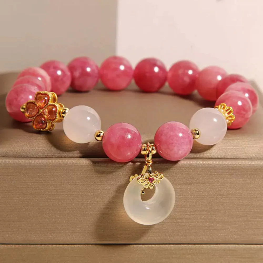 Bracelet "Douceur Éclatante" avec des perles de tourmaline rose et de jade blanc, orné d'un pendentif rond en jade et d'un trèfle en or.