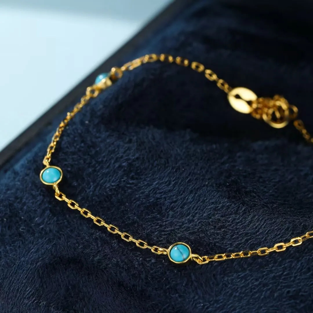 Bracelet fin en argent doré avec trois petites pierres de turquoise rondes serties sur une chaîne délicate.