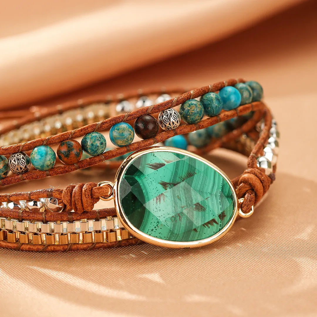 Bracelet wrap en cuir brun avec une grande pierre centrale en malachite verte facettée, entourée de perles bleues et de perles métalliques argentées.