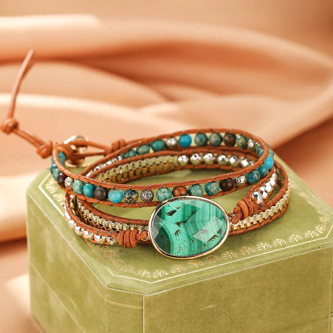 Bracelet jonc enroulé en cuir marron avec des perles bleues et une grande pierre de malachite verte ovale au centre.