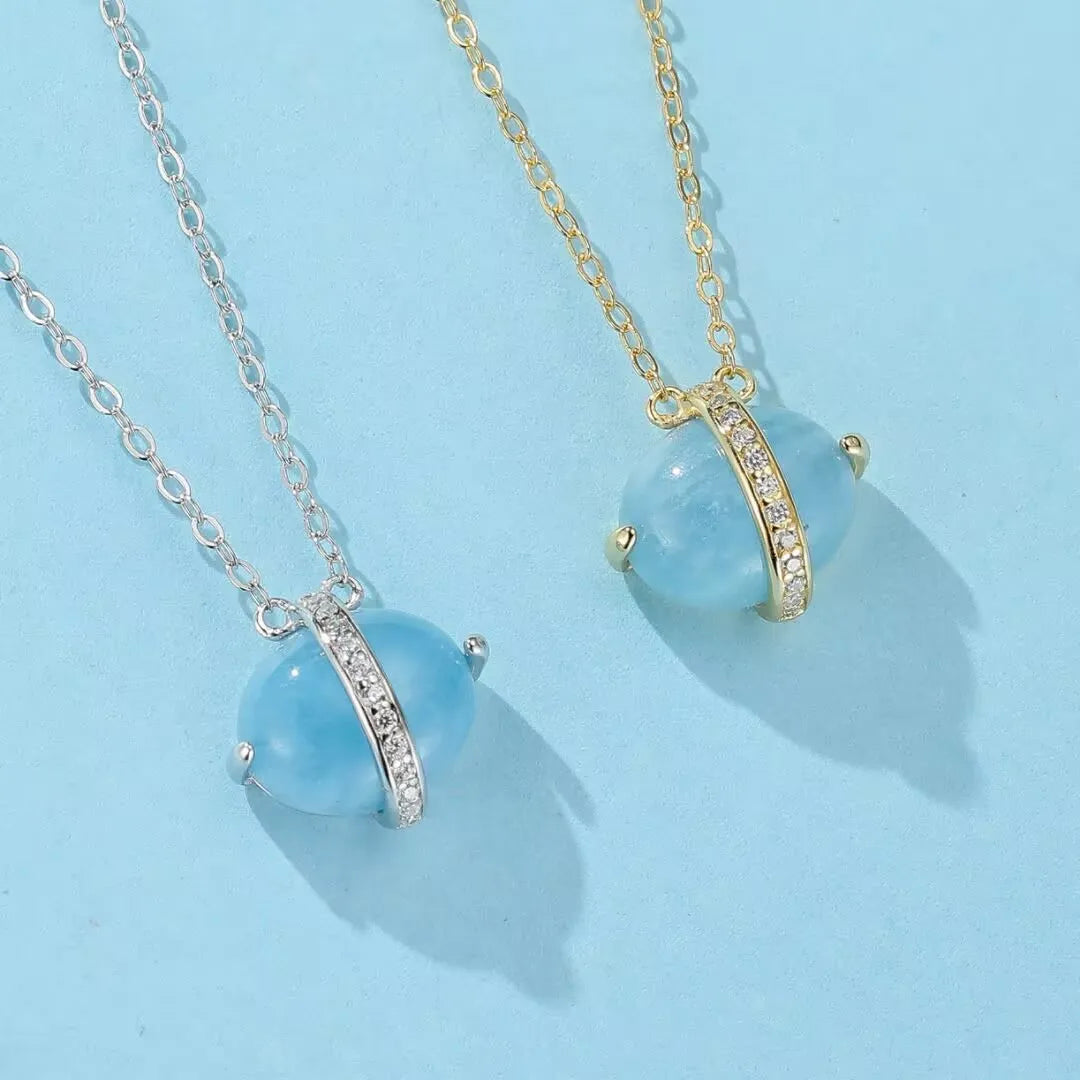 Deux colliers avec des pendentifs ovales en aigue-marine bleue, sertis dans un anneau orné de zircones cubiques, l'un en argent doré or 14K et l'autre en argent.