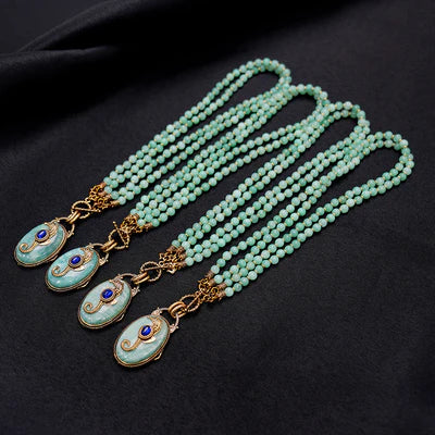 Collier "Voyage Marin" en Amazonite composé de plusieurs rangs de perles fines et d'un pendentif ovale bleu ciel orné d'une pierre bleue centrale et de détails dorés.