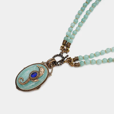 Collier "Voyage Marin" avec pendentif ovale en amazonite orné d'un hippocampe doré et d'une pierre bleue, monté sur deux rangs de perles d'amazonite.