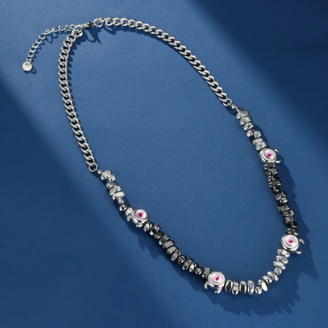 Collier pour homme en hématite avec des perles noires et roses formant un motif d'œil, sur fond bleu