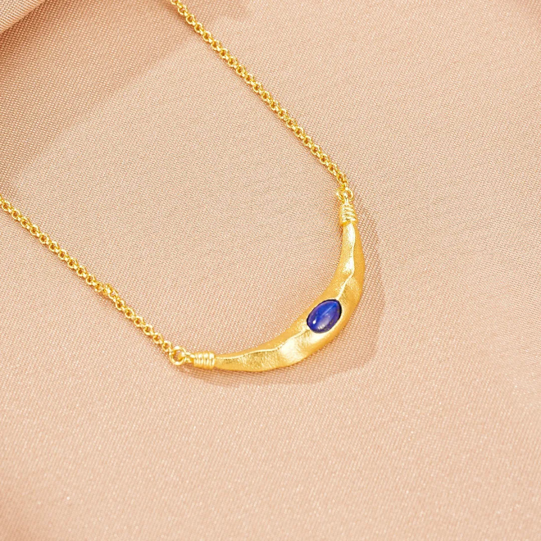 Collier en argent doré "Allure Mystique" avec un pendentif en forme de croissant de lune martelé incrusté d'une pierre bleue lapis-lazuli.