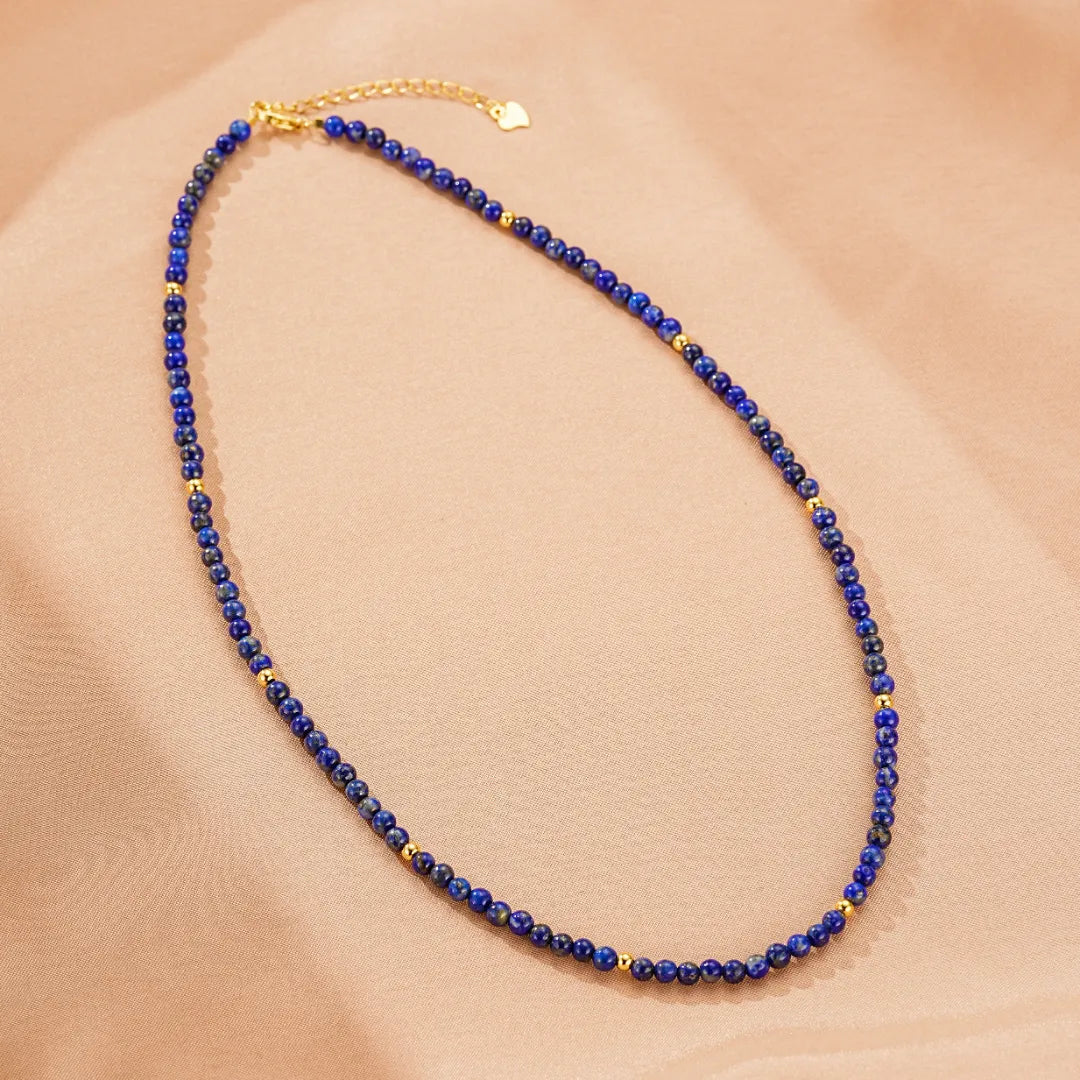 Collier ras du cou en lapis lazuli avec de petites perles dorées et un fermoir réglable avec un petit cœur doré.