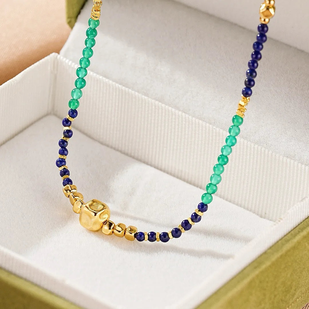 Collier artisanal "Sagesse Intérieure" en argent doré or, orné de perles de Lapis Lazuli bleues et de Jade vertes, avec un pendentif cubique central doré.