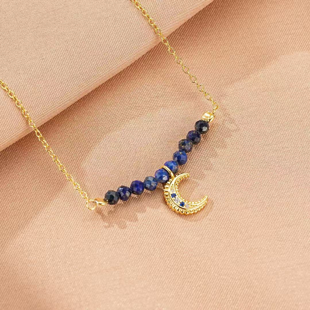 Collier "Nuit Sage" en argent doré à l'or 18 carats avec des perles de lapis-lazuli et un pendentif croissant de lune serti de petites pierres bleues.