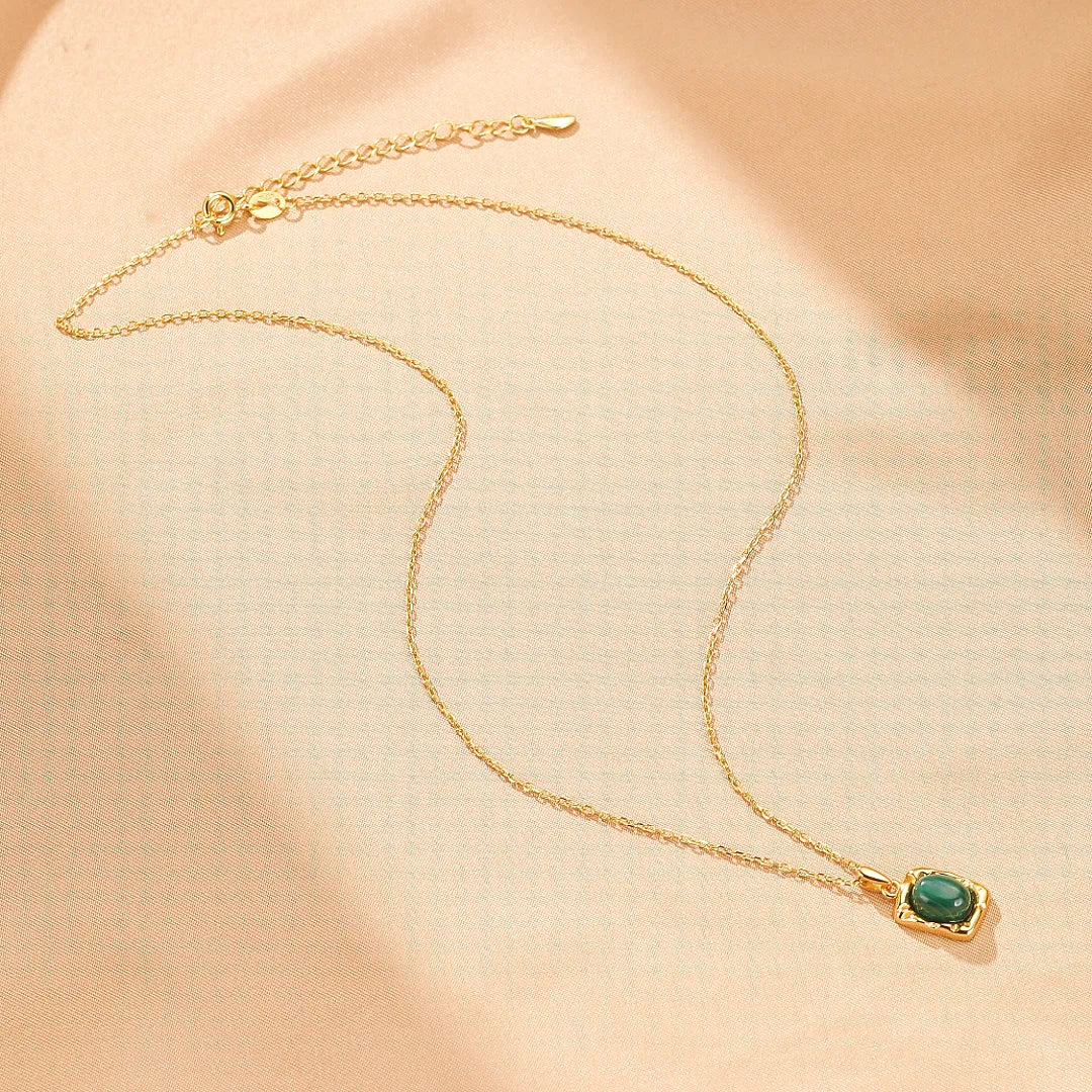 Collier en argent avec une pierre de malachite verte en forme de coussin, monté sur une fine chaîne dorée. Design élégant et intemporel.