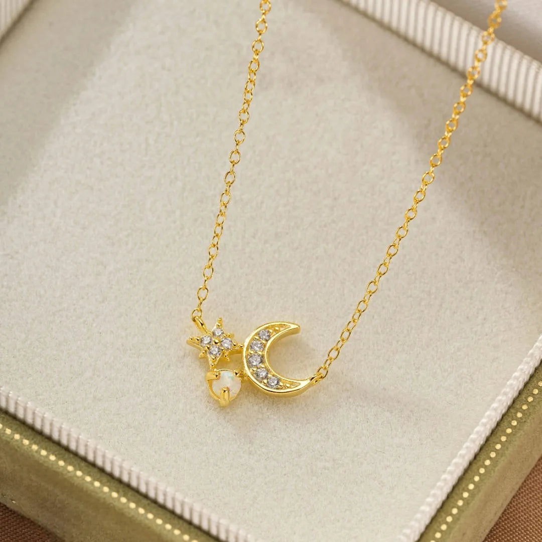 Collier en argent doré à l'or 18 carats avec un pendentif en forme de croissant de lune orné de zirconiums, une étoile scintillante et une petite opale blanche.