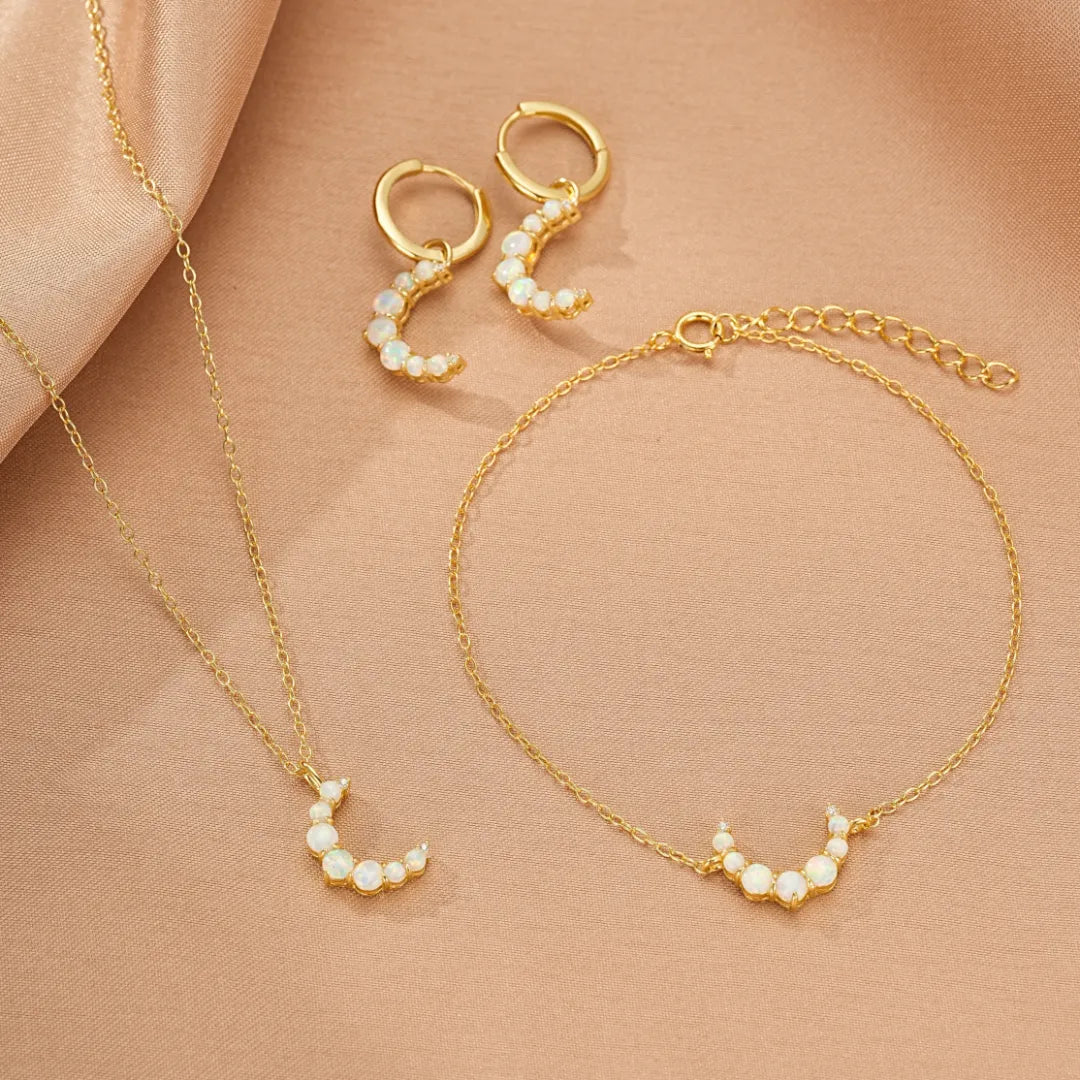 Ensemble de bijoux "Lune Douce" en argent doré 18 carats, comprenant un collier, une paire de boucles d'oreilles créoles et un bracelet, ornés de petites opales formant des croissants de lune.