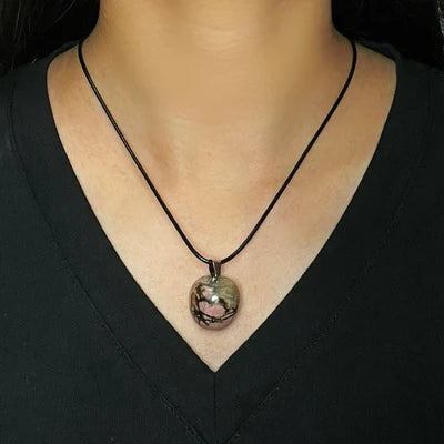 Collier ras du cou avec pendentif en rhodonite brute, de forme ovale, aux nuances roses et grises, porté par une femme.