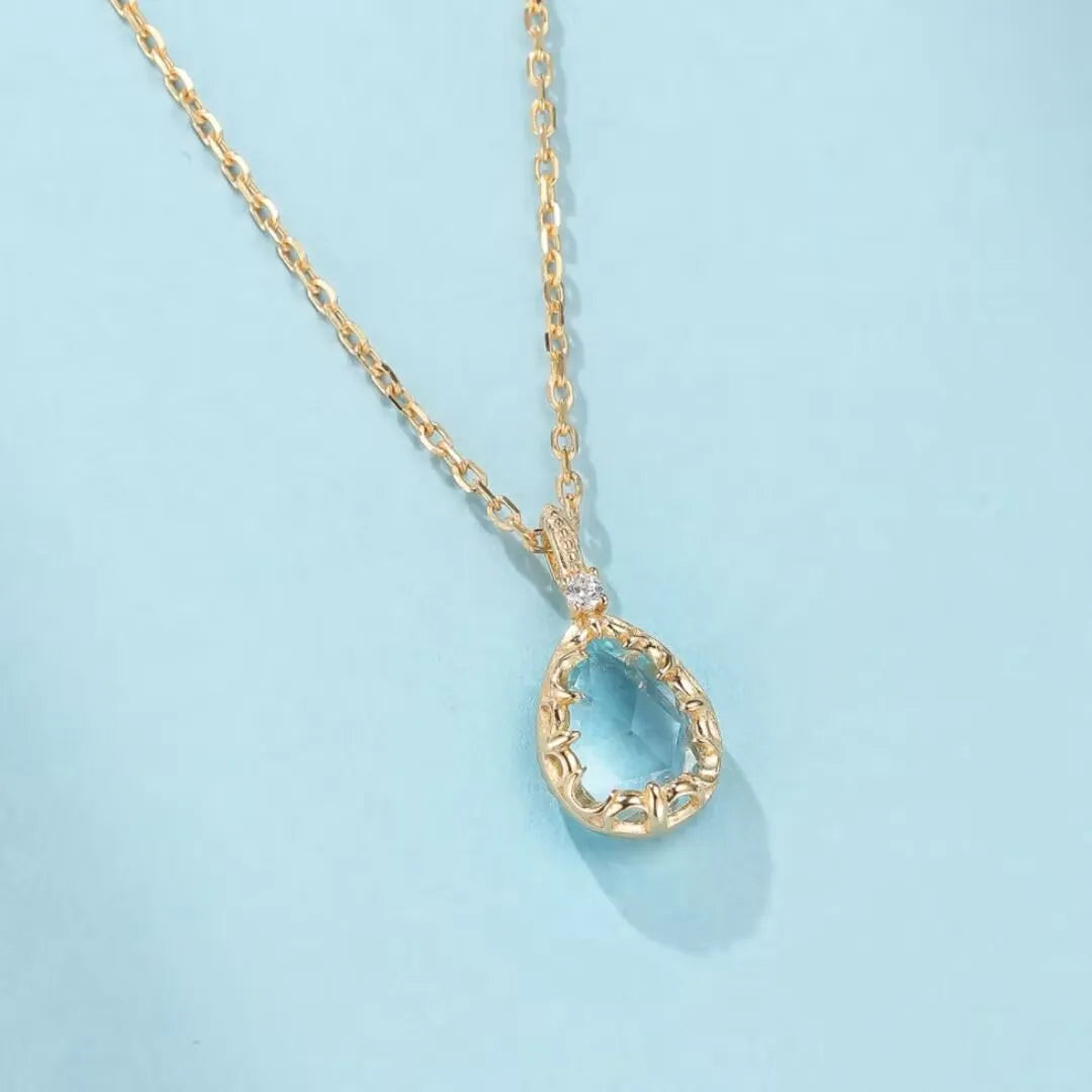 Collier "Éclat Marin" en argent 925 doré à l'or 14K avec une topaze bleue en forme de goutte et un petit diamant incrusté.