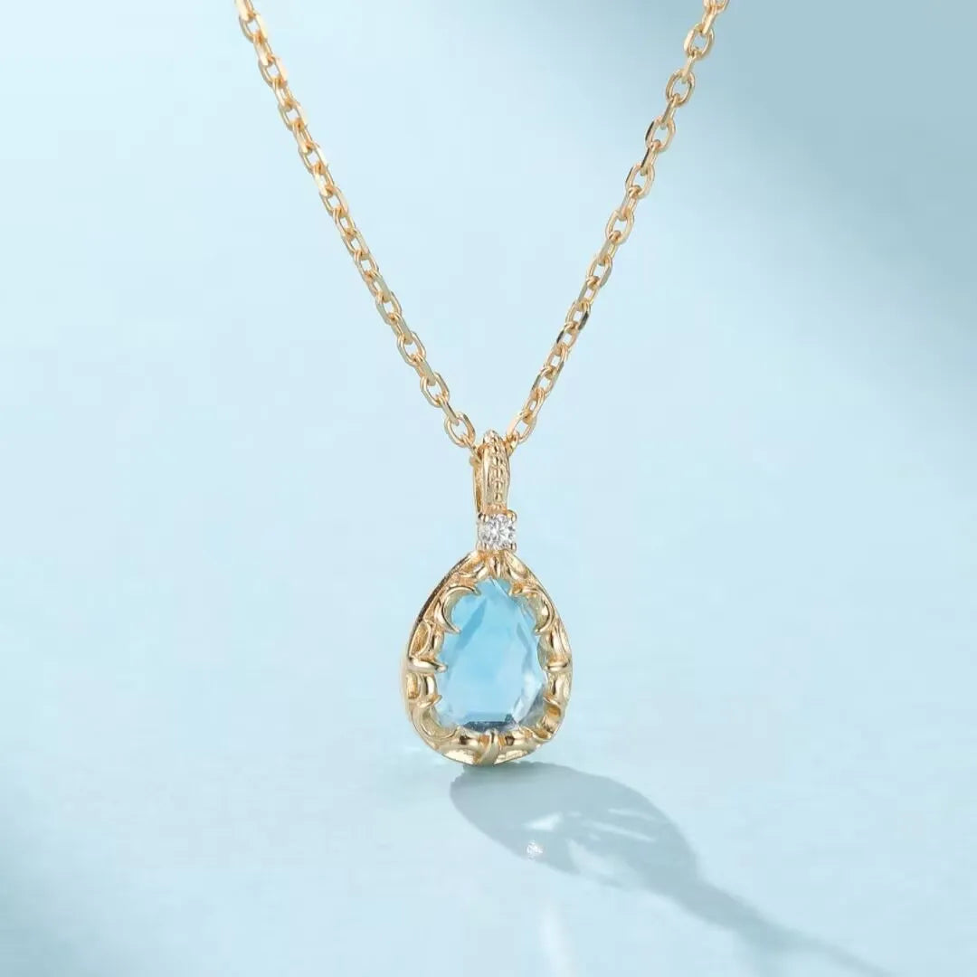 Collier "Éclat Marin" en argent 925 doré à l'or 14K, orné d'une topaze bleue en forme de goutte et d'un petit diamant.