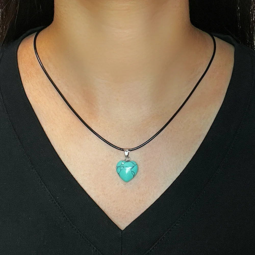 Collier avec un pendentif en forme de cœur en turquoise brute, porté sur un cordon noir autour du cou.