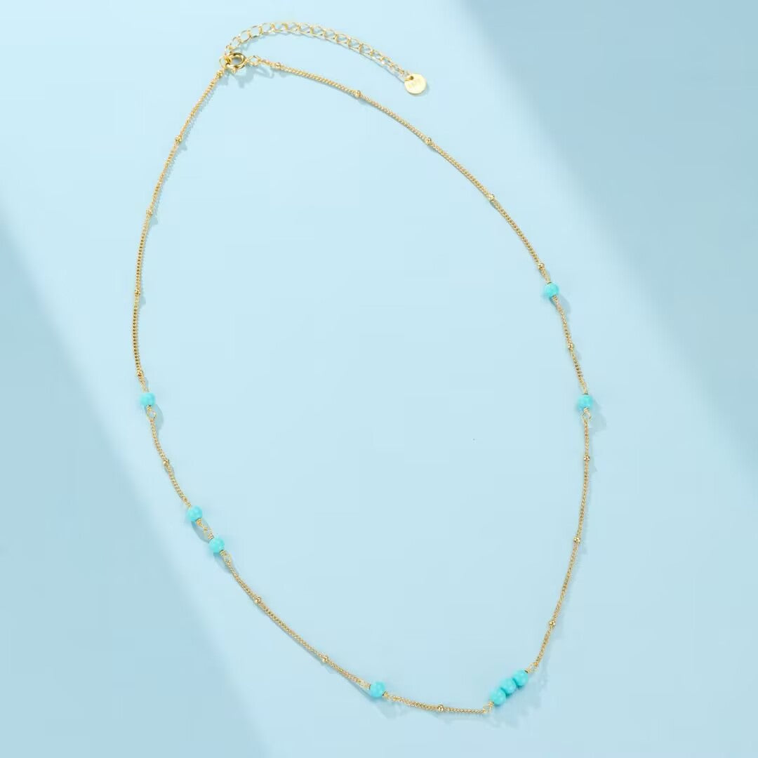 Collier "Dunes de Charme" en argent doré or, orné de petites perles turquoise disposées le long d'une fine chaîne.