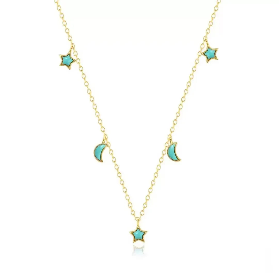 Collier "Équilibre Céleste" en argent doré or, orné de petites étoiles et lunes en turquoise bleue, sur fond blanc.