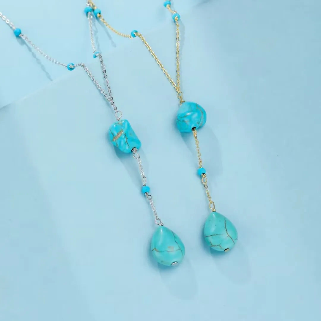 Deux colliers "Voyage Céleste" en argent, ornés de pierres de turquoise bleue naturelle de différentes formes et tailles, sur fond bleu pastel.