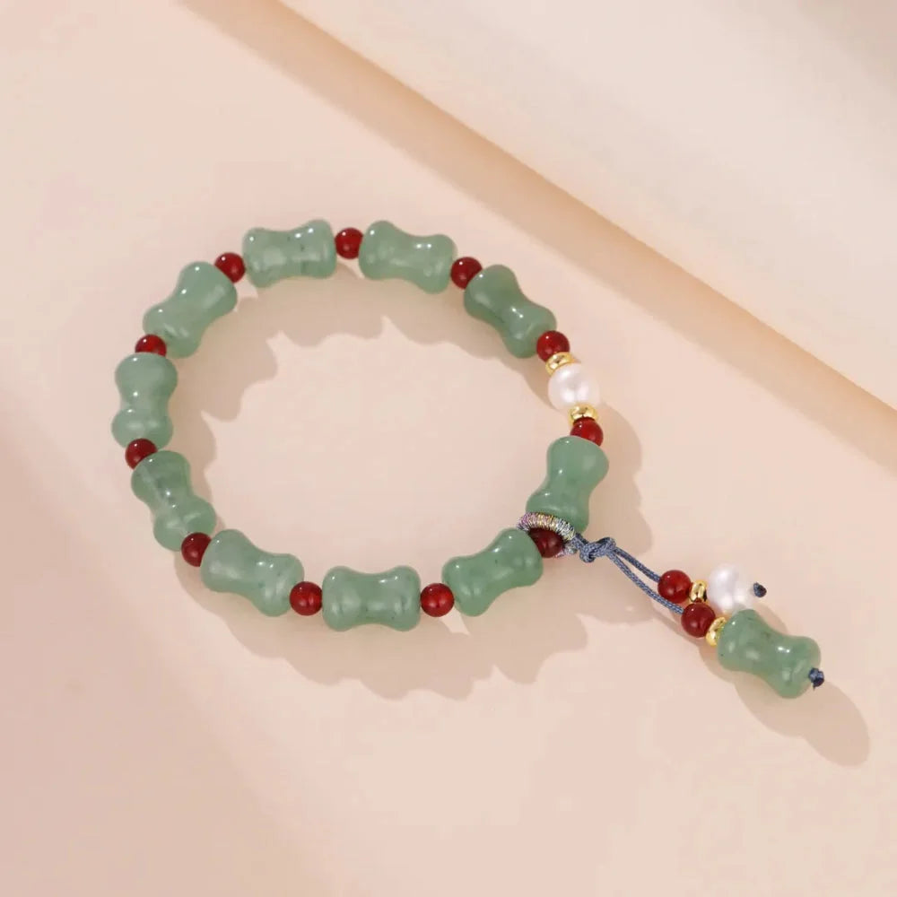 Bracelet fait de perles d'aventurine verte, de perles rouges et d'une perle nacrée, avec un fermoir en cordon bleu.