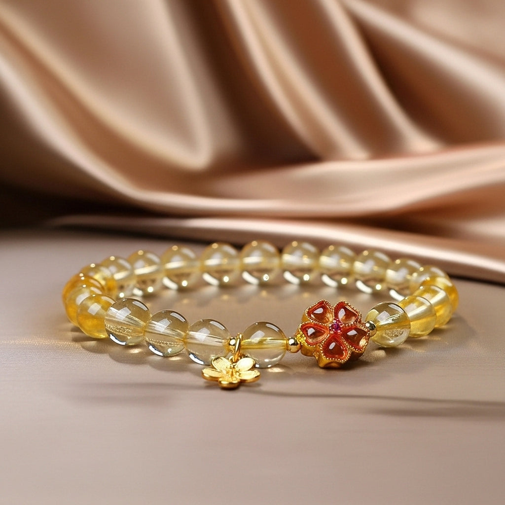 Bracelet en citrine naturelle avec breloque fleur dorée et fermoir orné de pierres rouges