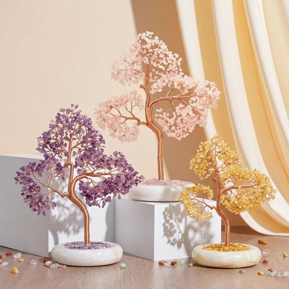 Trois arbres de vie décoratifs en pierres naturelles : un violet (améthyste), un rose (quartz rose) et un jaune (citrine), posés sur des socles en marbre blanc.